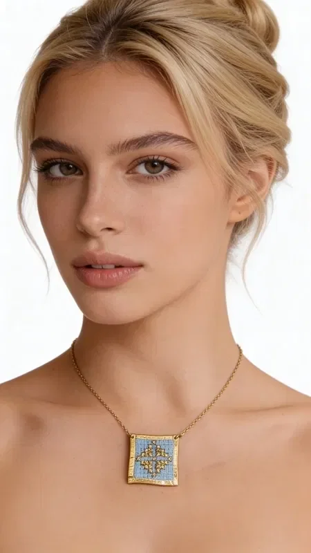 , This exceptional embroidered necklace in light blue with geometric patterns is a unique combination of traditional craftsmanship and contemporary design. Designed by Greek Jewelry Designer Aikaterini Chalkiadaki, every detail is hand-embroidered with gold thread on a light blue fabric background, creating a truly distinctive piece of jewelry.

The square embroidered motif features colorful geometric patterns inspired by Greek folklore, while the gold-toned brass frame adds elegance and durability. The delicate gold chain makes this necklace ideal for both everyday and evening looks.

This statement necklace pairs perfectly with monochrome outfits, adding color and character to your look. Handmade construction and quality materials guarantee the longevity of the piece.

Store the necklace in a dry place and clean gently with a soft cloth to preserve the vivid colors of the embroidery.