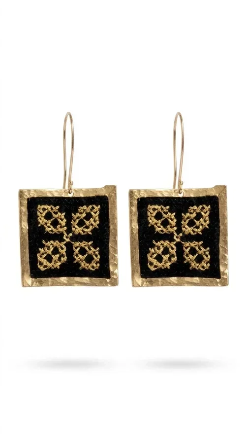 , The embroidered statement earrings with geometric patterns in black are the ideal choice for those seeking a piece of jewelry that combines folk tradition with modern design. Designed by Greek Jewelry Designer Aikaterini Chalkiadaki, these handmade earrings are a unique piece that stands out instantly thanks to their square shape and striking embroidery with golden details on black fabric.

Made from brass and fabric, these earrings feature a geometric motif inspired by folklore aesthetics — four symmetrical embroidered elements in a gold tone are framed by a golden brass frame, creating a result reminiscent of traditional Greek handicrafts. They hang from a gold hook and add movement and character to any look.

Ideal for weddings, christenings, evening outings, or even to elevate a casual everyday look, these statement earrings pair beautifully with both white outfits and neutral colors, as shown in the photo.