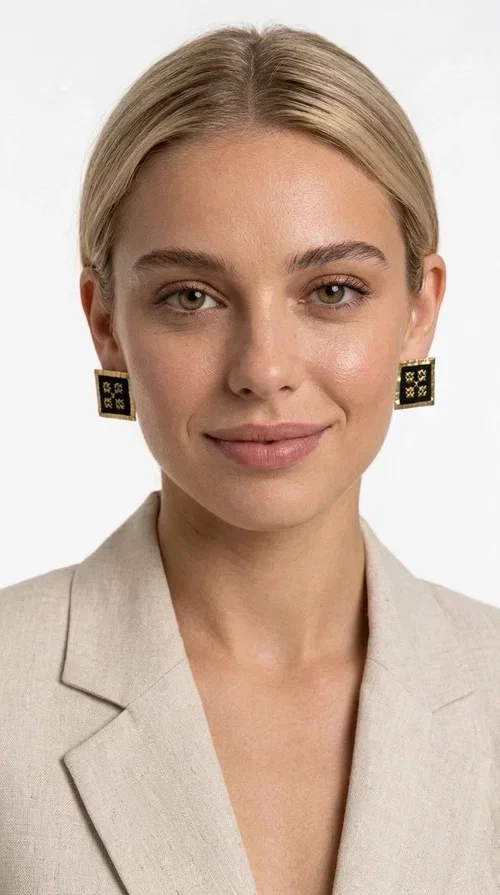 , The embroidered statement earrings with geometric patterns in black are the ideal choice for every woman who wants to express her uniqueness through her accessories. Featuring a square shape, a gold-toned brass frame and embroidered floral motifs on black fabric, these handmade earrings combine the traditional art of embroidery with a modern, striking result. Designed by Greek Jewelry Designer Aikaterini Chalkiadaki, they reflect Greek handcraft tradition with a contemporary touch.

The square brass structure with a gold hue perfectly frames the embroidered piece of fabric, where four symmetrical floral motifs in gold stand out, giving a folklore aesthetic with a bold, statement character. These stud earrings suit both casual and formal looks equally well — from an everyday outfit to a wedding or an evening out.