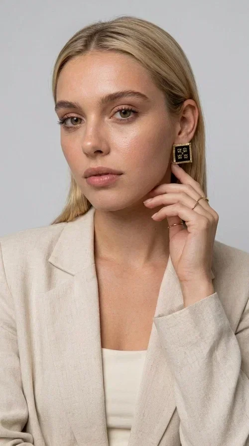 , The embroidered statement earrings with geometric patterns in black are the ideal choice for every woman who wants to express her uniqueness through her accessories. Featuring a square shape, a gold-toned brass frame and embroidered floral motifs on black fabric, these handmade earrings combine the traditional art of embroidery with a modern, striking result. Designed by Greek Jewelry Designer Aikaterini Chalkiadaki, they reflect Greek handcraft tradition with a contemporary touch.

The square brass structure with a gold hue perfectly frames the embroidered piece of fabric, where four symmetrical floral motifs in gold stand out, giving a folklore aesthetic with a bold, statement character. These stud earrings suit both casual and formal looks equally well — from an everyday outfit to a wedding or an evening out.