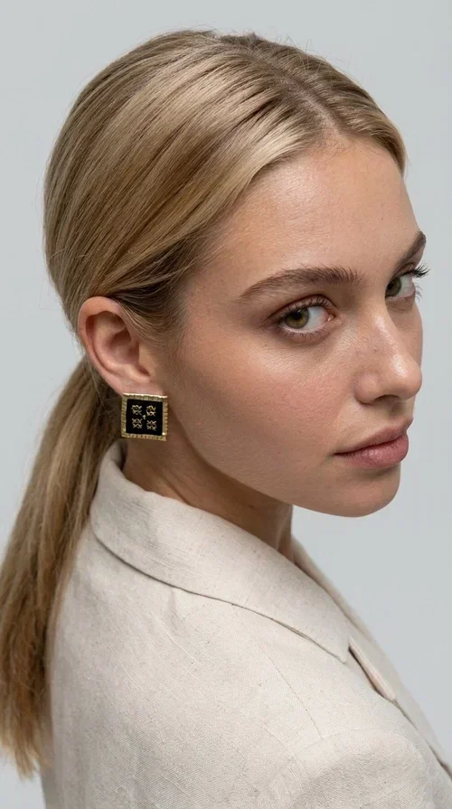 , The embroidered statement earrings with geometric patterns in black are the ideal choice for every woman who wants to express her uniqueness through her accessories. Featuring a square shape, a gold-toned brass frame and embroidered floral motifs on black fabric, these handmade earrings combine the traditional art of embroidery with a modern, striking result. Designed by Greek Jewelry Designer Aikaterini Chalkiadaki, they reflect Greek handcraft tradition with a contemporary touch.

The square brass structure with a gold hue perfectly frames the embroidered piece of fabric, where four symmetrical floral motifs in gold stand out, giving a folklore aesthetic with a bold, statement character. These stud earrings suit both casual and formal looks equally well — from an everyday outfit to a wedding or an evening out.