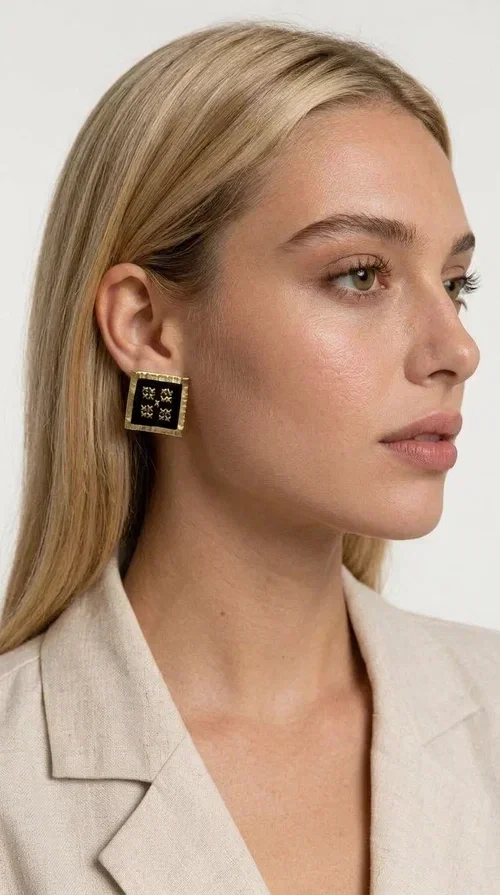 , The embroidered statement earrings with geometric patterns in black are the ideal choice for every woman who wants to express her uniqueness through her accessories. Featuring a square shape, a gold-toned brass frame and embroidered floral motifs on black fabric, these handmade earrings combine the traditional art of embroidery with a modern, striking result. Designed by Greek Jewelry Designer Aikaterini Chalkiadaki, they reflect Greek handcraft tradition with a contemporary touch.

The square brass structure with a gold hue perfectly frames the embroidered piece of fabric, where four symmetrical floral motifs in gold stand out, giving a folklore aesthetic with a bold, statement character. These stud earrings suit both casual and formal looks equally well — from an everyday outfit to a wedding or an evening out.