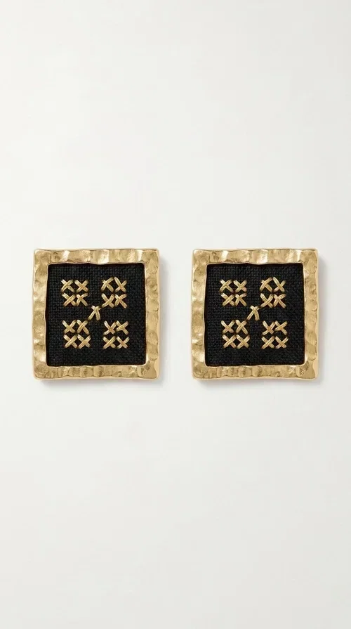 , The embroidered statement earrings with geometric patterns in black are the ideal choice for every woman who wants to express her uniqueness through her accessories. Featuring a square shape, a gold-toned brass frame and embroidered floral motifs on black fabric, these handmade earrings combine the traditional art of embroidery with a modern, striking result. Designed by Greek Jewelry Designer Aikaterini Chalkiadaki, they reflect Greek handcraft tradition with a contemporary touch.

The square brass structure with a gold hue perfectly frames the embroidered piece of fabric, where four symmetrical floral motifs in gold stand out, giving a folklore aesthetic with a bold, statement character. These stud earrings suit both casual and formal looks equally well — from an everyday outfit to a wedding or an evening out.