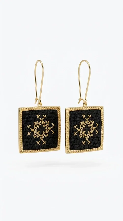 , Embroidered statement earrings with geometric patterns in black are the ideal choice for those seeking jewelry that combines the traditional art of embroidery with a modern, striking result. Designed by Greek Jewelry Designer Aikaterini Chalkiadaki, these handmade earrings are a unique piece of folklore aesthetic that immediately stands out.

Made of brass and fabric, the earrings feature a square, diamond-shaped pendant in deep black, decorated with a golden geometric motif reminiscent of the Greek folk embroidery tradition. Their golden brass metal frame adds elegance and contrast, while the overall result is dynamic yet refined.

These striking dangle earrings suit both casual and formal looks — from an everyday combination with a linen blazer to an evening look for a wedding or christening. They particularly enhance updos and loose hair.