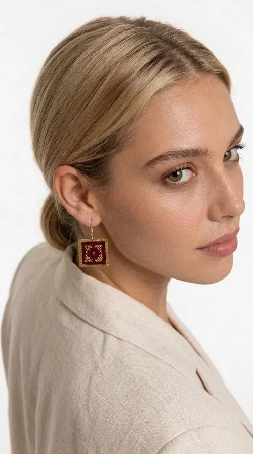 , These embroidered statement earrings in deep burgundy are the perfect choice for those seeking jewelry with character, combining the traditional art of embroidery with contemporary aesthetics.

Designed by Greek Jewelry Designer Aikaterini Chalkiadaki, these handmade earrings feature a square brass frame in gold tone, with a finely detailed embossed surface that highlights their premium quality. Inside, deep red fabric in a burgundy shade is adorned with geometric cross-stitch embroidery designs — a nod to folk tradition that takes on a modern, urban character.

These dangle earrings pair equally well with casual and formal outfits, from everyday looks to appearances at weddings, christenings, or corporate events. Their burgundy color makes them ideal for autumn and winter looks, while their statement aesthetic guarantees they won't go unnoticed.