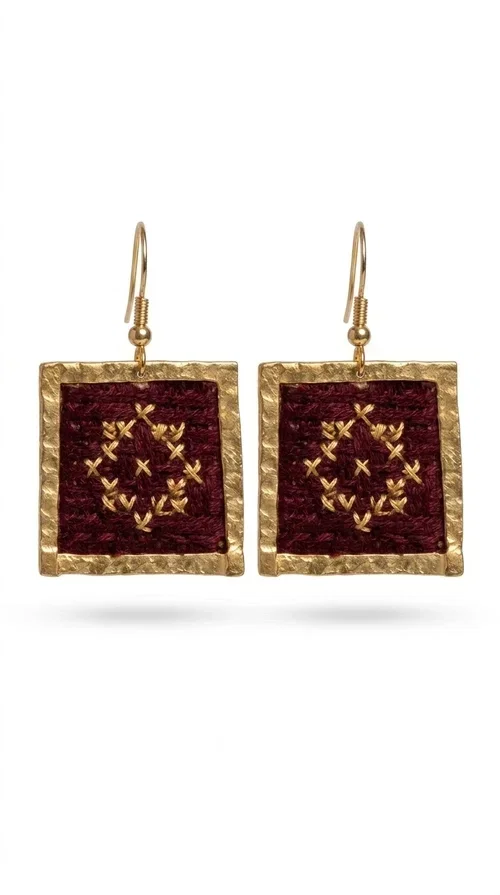 , Embroidered statement earrings with geometric designs in deep burgundy are the ideal choice for every woman who wants to express herself through her jewelry. Designed by Greek Jewelry Designer Aikaterini Chalkiadaki, these handmade earrings combine the traditional art of embroidery with a modern, striking aesthetic that stands out.

The square shape in golden brass frames an embroidered fabric in a rich burgundy color, with detailed geometric motifs reminiscent of folklore tradition. The gold threads of the embroidery create a warm contrast with the deep red background, lending an air of boho-folk elegance. The delicate pendant connection ensures comfortable wear and graceful movement.

Ideal for weddings, christenings, festive dinners, and also for elevating an everyday outfit, these earrings pair perfectly with linen, velvet, or solid-colored clothing. Burgundy is a timeless color that pairs especially well with earthy tones, beige, and gold.