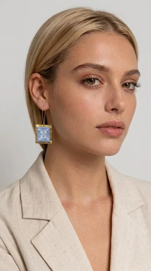, The embroidered statement earrings with geometric designs in light blue are a bold choice for every woman who wants to express herself through her jewelry. Designed by Greek Jewelry Designer Aikaterini Chalkiadaki, these striking handmade earrings combine the traditional art of embroidery with a modern, geometric aesthetic.

Their square shape, featuring a gold-tone brass hoop, highlights the light blue embroidered fabric adorned with delicate geometric details — a result that evokes Greek folk art and a folklore aesthetic. Each pair is unique thanks to its handmade craftsmanship, making it a true treasure for your collection.

Ideal for weddings, christenings, formal occasions, and even for elevating an everyday look, these earrings pair beautifully with white, ecru, or blue outfits. Lightweight to wear and comfortable to have on.