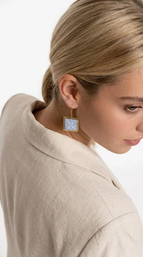 , The embroidered statement earrings with geometric designs in light blue are a bold choice for every woman who wants to express herself through her jewelry. Designed by Greek Jewelry Designer Aikaterini Chalkiadaki, these striking handmade earrings combine the traditional art of embroidery with a modern, geometric aesthetic.

Their square shape, featuring a gold-tone brass hoop, highlights the light blue embroidered fabric adorned with delicate geometric details — a result that evokes Greek folk art and a folklore aesthetic. Each pair is unique thanks to its handmade craftsmanship, making it a true treasure for your collection.

Ideal for weddings, christenings, formal occasions, and even for elevating an everyday look, these earrings pair beautifully with white, ecru, or blue outfits. Lightweight to wear and comfortable to have on.