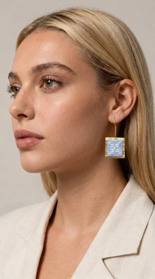 , The embroidered statement earrings with geometric designs in light blue are a bold choice for every woman who wants to express herself through her jewelry. Designed by Greek Jewelry Designer Aikaterini Chalkiadaki, these striking handmade earrings combine the traditional art of embroidery with a modern, geometric aesthetic.

Their square shape, featuring a gold-tone brass hoop, highlights the light blue embroidered fabric adorned with delicate geometric details — a result that evokes Greek folk art and a folklore aesthetic. Each pair is unique thanks to its handmade craftsmanship, making it a true treasure for your collection.

Ideal for weddings, christenings, formal occasions, and even for elevating an everyday look, these earrings pair beautifully with white, ecru, or blue outfits. Lightweight to wear and comfortable to have on.