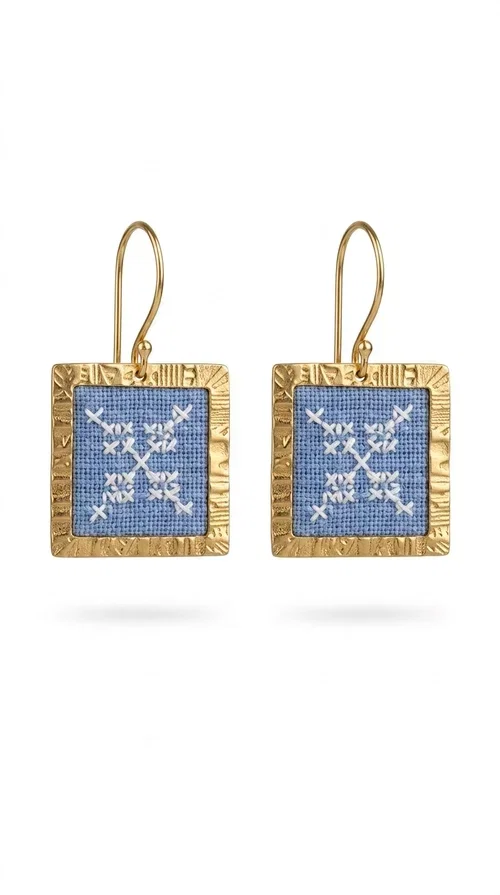 , The embroidered statement earrings with geometric designs in light blue are a bold choice for every woman who wants to express herself through her jewelry. Designed by Greek Jewelry Designer Aikaterini Chalkiadaki, these striking handmade earrings combine the traditional art of embroidery with a modern, geometric aesthetic.

Their square shape, featuring a gold-tone brass hoop, highlights the light blue embroidered fabric adorned with delicate geometric details — a result that evokes Greek folk art and a folklore aesthetic. Each pair is unique thanks to its handmade craftsmanship, making it a true treasure for your collection.

Ideal for weddings, christenings, formal occasions, and even for elevating an everyday look, these earrings pair beautifully with white, ecru, or blue outfits. Lightweight to wear and comfortable to have on.