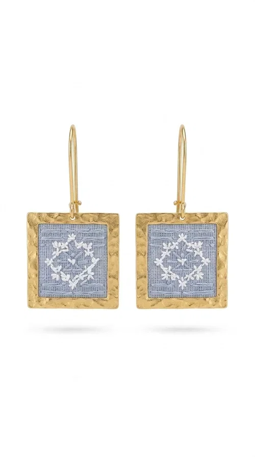 , The embroidered statement earrings with geometric patterns in light blue are the perfect choice for every woman who wants to express her personality in a unique, handmade way. With their striking square shape and finely crafted folk-inspired geometric motifs in shades of light blue, these earrings combine the traditional art of embroidery with a completely modern aesthetic result.

Designed by Greek Jewelry Designer Aikaterini Chalkiadaki, they are handcrafted from brass and fabric, creating a piece of jewelry that highlights the detail and craftsmanship of Greek artistry. The golden brass metal frame surrounds the embroidered fabric featuring light blue geometric motifs with a folklore aesthetic, resulting in a look reminiscent of contemporary boho-chic elegance.

Ideal for weddings, christenings, formal events, but also for everyday chic looks, they pair perfectly with white, ecru, or monochrome outfits. Hanging from a gold-tone hook, they move gently, adding motion and vitality to your look.