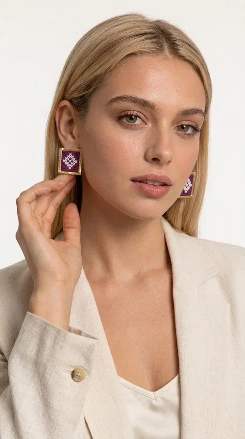 , The embroidered statement earrings with geometric patterns in magenta are the ideal choice for every woman who wants to express herself through unique, handmade jewelry. Designed by Greek Jewelry Designer Aikaterini Chalkiadaki, these striking stud earrings combine the traditional art of embroidery with a modern aesthetic result, creating a piece of jewelry that truly stands out.

Each pair consists of square earrings with gold brass framing embroidered fabric in a vivid magenta color, decorated with delicate geometric motifs in white — a combination that evokes folklore aesthetics and Greek tradition. The result is a jewelry piece with character, instantly elevating any look, from casual outfits to formal events.

Ideal for weddings, christenings, summer events, or everyday looks you want to make a statement with, these handmade earrings pair perfectly with white, ecru, or monochrome outfits.