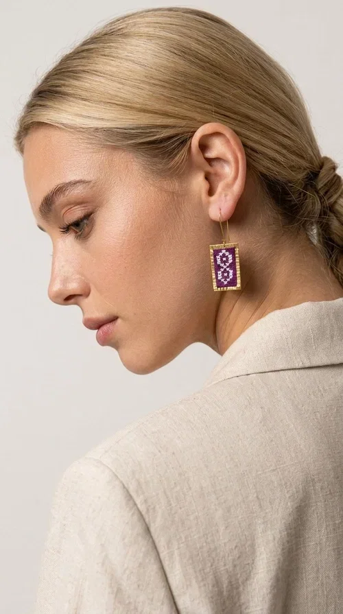 , The embroidered statement earrings with geometric designs in magenta are the ideal choice for every woman who wants to stand out with style and character. Designed by Greek Jewelry Designer Aikaterini Chalkiadaki, these handmade earrings combine the traditional art of embroidery with a modern, striking result that won't go unnoticed.

Each pair features a rectangular shape with gold-tone brass elegantly framing the embroidered fabric, creating an impressive result that evokes Greek folk tradition. The geometric motifs in deep magenta and lilac give the earrings a boho-chic character that suits both everyday looks and formal occasions, such as weddings, christenings, and festive events.

Wear them with a simple white shirt to draw attention to your face, or pair them with a boho dress for a complete, harmonious outfit. These dangling hoop earrings belong to the category of statement jewelry that elevates any look to another level.