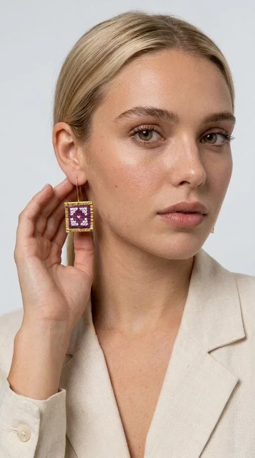 , The embroidered statement earrings in a vibrant magenta shade are the definition of jewelry that never goes unnoticed — a bold choice for those who love to express themselves through their style.

Designed by Greek Jewelry Designer Aikaterini Chalkiadaki, these striking handmade earrings combine geometric embroidered patterns in magenta and white, set within a square brass frame in a gold hue. The embroidery technique adds depth and texture to the piece, bringing forward a folk and folklore aesthetic that nods to Greek tradition in a modern way.

The dangling design with a delicate hook lets the earrings sway elegantly, elevating every look — from casual everyday outfits to evening outings, weddings, or festive occasions. The bold magenta hue pairs beautifully with neutral colors (white, beige, black) as well as with daring color combinations.