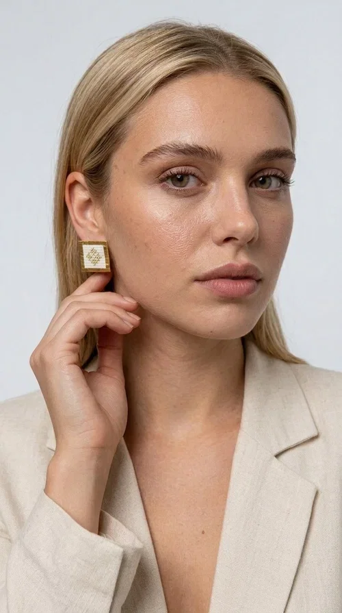 , Embroidered statement earrings with geometric designs in white are the ideal choice for those seeking an accessory that combines traditional craftsmanship with contemporary style. Designed by Greek Jewelry Designer Aikaterini Chalkiadaki, these handmade earrings are a unique piece that exudes authenticity and creativity.

These striking stud earrings feature a square shape with a gold-toned brass frame and white fabric embroidery in geometric patterns inspired by Greek folk tradition. The use of brass and fabric gives them a distinctive boho-folklore character that suits both casual and formal outfits perfectly.

Ideal for weddings, christenings, evening outings, and everyday wear, these embroidered earrings elevate any outfit in a subtly striking way. Pair them with a linen blazer or a boho dress for a complete look.
