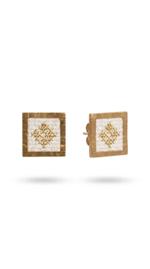 , Embroidered statement earrings with geometric designs in white are the ideal choice for those seeking an accessory that combines traditional craftsmanship with contemporary style. Designed by Greek Jewelry Designer Aikaterini Chalkiadaki, these handmade earrings are a unique piece that exudes authenticity and creativity.

These striking stud earrings feature a square shape with a gold-toned brass frame and white fabric embroidery in geometric patterns inspired by Greek folk tradition. The use of brass and fabric gives them a distinctive boho-folklore character that suits both casual and formal outfits perfectly.

Ideal for weddings, christenings, evening outings, and everyday wear, these embroidered earrings elevate any outfit in a subtly striking way. Pair them with a linen blazer or a boho dress for a complete look.