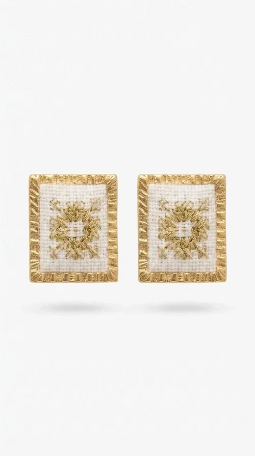 , Embroidered statement earrings with geometric patterns are the ideal choice for every woman who wants to add a unique touch to her style, combining the traditional art of embroidery with a modern, striking result. Designed by Greek Jewelry Designer Aikaterini Chalkiadaki, these handmade earrings are a tribute to detail and Greek craftsmanship.

Square in shape with a white fabric base, the earrings are decorated with gold-tone geometric embroidery inspired by folklore and ethnic aesthetics. The gold-toned brass border gives them structure and shine, while the combination of white and gold makes them easy to pair with casual, boho, and even more formal outfits. When worn, they highlight the face without overwhelming it — the perfect statement piece for any occasion.

Ideal for weddings, christenings, summer evening outings, or to elevate an everyday look, these earrings pair beautifully with linen, cotton, and boho outfits. They also make a distinctive gift for any woman who loves handmade jewelry with character.