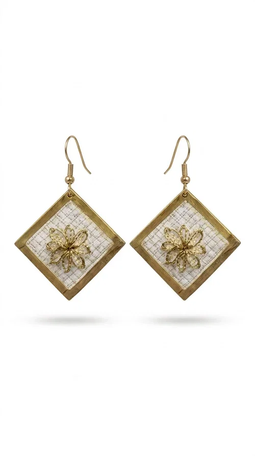 , The embroidered statement earrings with geometric patterns in white and gold are the perfect choice for those seeking a piece of jewelry that combines folk art with contemporary design. Designed by Greek Jewelry Designer Aikaterini Chalkiadaki, these handmade dangle earrings impress with their geometric diamond shape and the embroidered floral decoration at their center.

Made of brass and fabric, they feature a gold frame surrounding a white embroidered section with a raised floral motif — a detail that evokes traditional Greek embroidery art. They hang from a gold hoop, creating an elegant yet striking result. Ideal as earrings for a wedding, christening or any formal event, but also as a boho statement piece for casual looks.