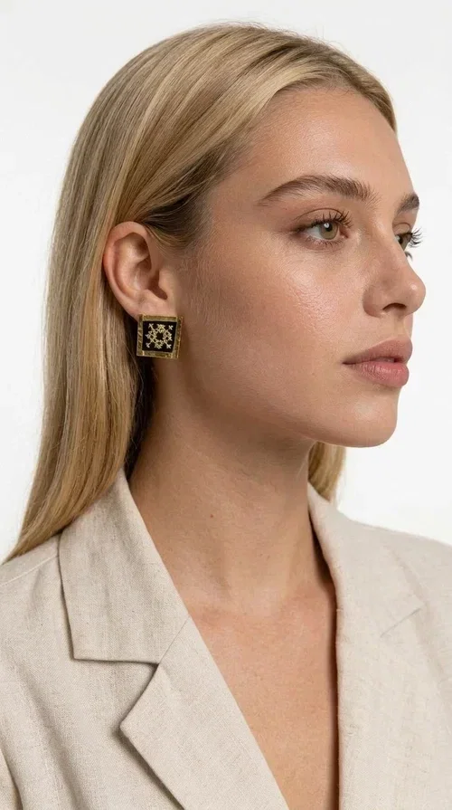 , The embroidered statement earrings with geometric patterns in black are the ideal choice for those seeking an accessory that combines folk tradition with modern aesthetics. Designed by Greek Jewelry Designer Aikaterini Chalkiadaki, these handmade earrings are a small wearable work of art.

Each pair is made of brass and fabric, with embroidered motifs inspired by Greek folk art. Their square, flat shape and golden geometric patterns set against a black background create a striking visual contrast, making them stand out in any look. These stud earrings suit both casual and formal outfits equally well.

Wear them with a simple everyday look to instantly elevate it, or choose them for a wedding, an evening out, or a professional event. They also make a wonderful gift idea for women who appreciate handmade jewelry with character.