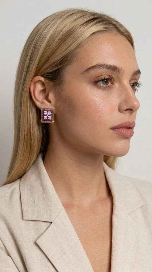 , The embroidered statement earrings with geometric designs in magenta are a bold choice for every woman who wants to express herself through her style. Designed by Greek Jewelry Designer Aikaterini Chalkiadaki, these handmade stud earrings combine folklore aesthetics with contemporary geometric composition, creating a result that immediately catches the eye.

Made from brass and fabric, they feature a square frame with a golden finish and an embroidered inner motif in a striking magenta shade, with delicate floral-geometric details reminiscent of traditional Greek folk art. The result is a jewelry piece with character and depth, ideal for elevating even the simplest outfit.

Perfect for weddings, christenings, nights out, or everyday looks that call for something extra, these earrings pair beautifully with white, black, or neutral clothing that lets the jewelry take center stage.