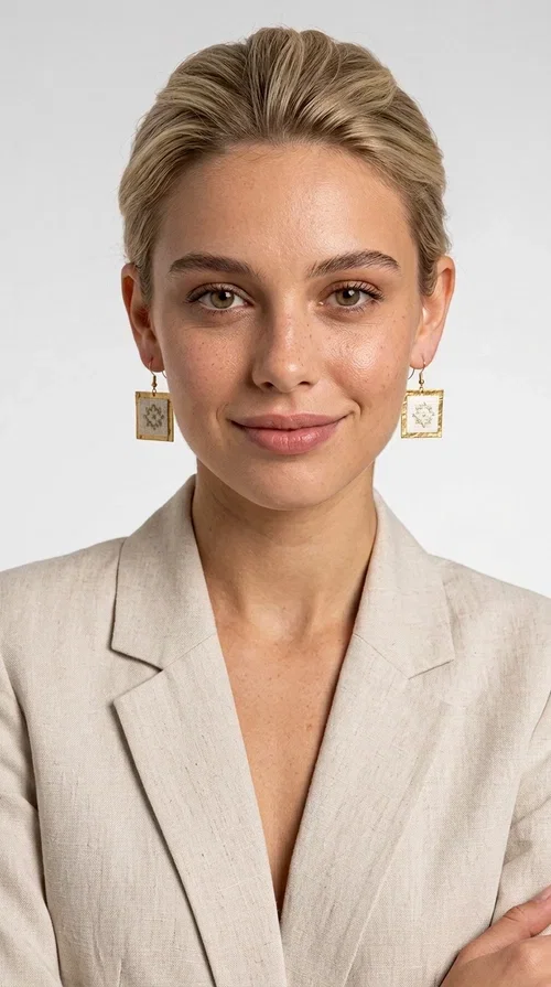, Embroidered statement earrings with geometric patterns in white are a bold choice for every woman who loves handmade jewelry with character and style. Designed by Greek Jewelry Designer Aikaterini Chalkiadaki, these striking earrings combine the traditional art of embroidery with a modern, geometric aesthetic that stands out.

Made from brass and fabric, the earrings feature a square shape with a gold-toned brass metal frame surrounding a finely embroidered white center adorned with floral and geometric motifs. The result is an accessory that evokes Greek folk tradition while fitting seamlessly into a modern, everyday or festive style.

Ideal for weddings, christenings, nights out, or even to elevate a simple office look, these earrings pair beautifully with linen, boho, or minimal outfits. The white palette makes them versatile and timeless.