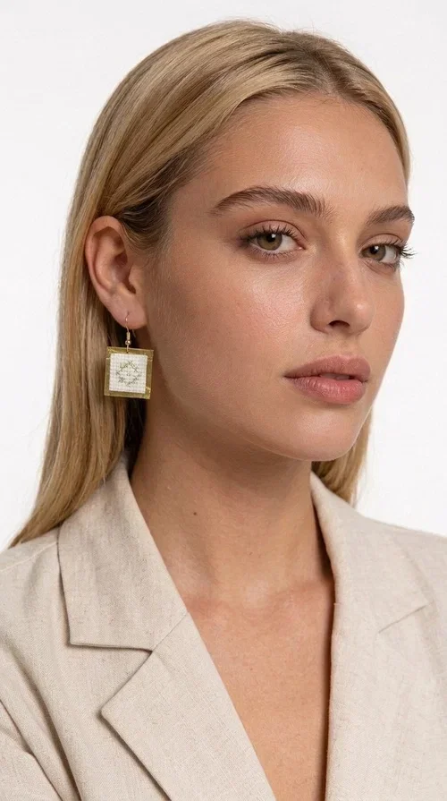 , Embroidered statement earrings with geometric patterns in white are a bold choice for every woman who loves handmade jewelry with character and style. Designed by Greek Jewelry Designer Aikaterini Chalkiadaki, these striking earrings combine the traditional art of embroidery with a modern, geometric aesthetic that stands out.

Made from brass and fabric, the earrings feature a square shape with a gold-toned brass metal frame surrounding a finely embroidered white center adorned with floral and geometric motifs. The result is an accessory that evokes Greek folk tradition while fitting seamlessly into a modern, everyday or festive style.

Ideal for weddings, christenings, nights out, or even to elevate a simple office look, these earrings pair beautifully with linen, boho, or minimal outfits. The white palette makes them versatile and timeless.