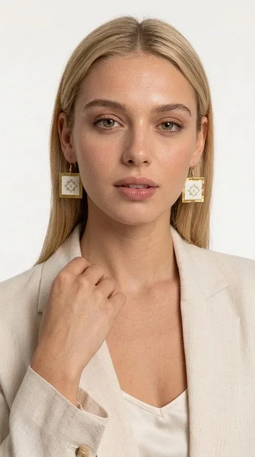 , Embroidered statement earrings with geometric patterns in white are a bold choice for every woman who loves handmade jewelry with character and style. Designed by Greek Jewelry Designer Aikaterini Chalkiadaki, these striking earrings combine the traditional art of embroidery with a modern, geometric aesthetic that stands out.

Made from brass and fabric, the earrings feature a square shape with a gold-toned brass metal frame surrounding a finely embroidered white center adorned with floral and geometric motifs. The result is an accessory that evokes Greek folk tradition while fitting seamlessly into a modern, everyday or festive style.

Ideal for weddings, christenings, nights out, or even to elevate a simple office look, these earrings pair beautifully with linen, boho, or minimal outfits. The white palette makes them versatile and timeless.