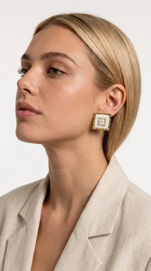 , Embroidered statement earrings with geometric patterns are the ideal choice for those seeking an accessory that combines folk tradition with a modern, minimalist aesthetic. Designed by Greek Jewelry Designer Aikaterini Chalkiadaki, these handmade stud earrings are a tribute to craftsmanship and Greek creativity.

Made from brass and fabric, the earrings feature a square shape on a white background with gold embroidery forming geometric motifs inspired by folk tradition. The result is a jewelry piece with strong character, lightweight to wear and particularly striking in appearance — ideal for both casual outfits and more formal occasions such as weddings, christenings, or professional events.

They pair perfectly with white, beige, or earth-tone clothing, while their square shape adds a modern, geometric element that elevates any look. A perfect gift for women who appreciate handmade jewelry with a Greek soul.