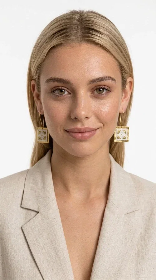 , Embroidered statement earrings with geometric designs are the ideal choice for those seeking an accessory that combines the traditional art of embroidery with contemporary design. Designed by Greek Jewelry Designer Aikaterini Chalkiadaki, these handmade earrings bring Greek aesthetics to the forefront in a bold and modern way.

Each pair features a square embroidered pendant in white with gold geometric details reminiscent of folk-inspired aesthetics. The gold-tone brass frame gives structure and elegance to the piece, while the hook clasp ensures comfortable and secure wear. The result is a piece of jewelry that immediately draws attention without being heavy or bulky.

Ideal for weddings, christenings, festive events, or even to elevate an everyday casual outfit, these particular drop earrings pair equally well with dresses, blazers, and boho-style looks.