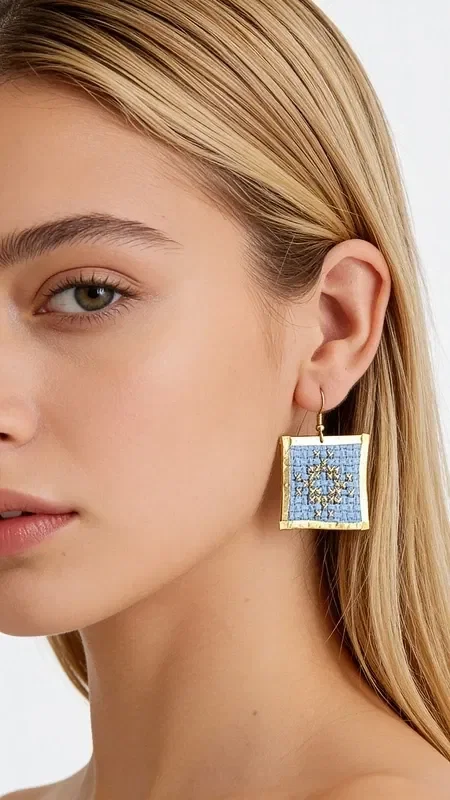 , The statement earrings with embroidered geometric patterns in light blue will become your favorite accessory for every special occasion. Designed by Greek Jewelry Designer Aikaterini Chalkiadaki, these striking handmade earrings combine the traditional art of embroidery with contemporary design.

The gold thread in a soft light blue shade creates a unique geometric motif that adds elegance and style to every look. These embroidered earrings have a square shape and medium size, ideal for making a statement without being overly heavy. Their detailed craftsmanship and folklore design make them special for evening outings, special events, or even bridal looks. Care for your earrings by storing them in a dry place and avoiding contact with water or chemical products to preserve their color.