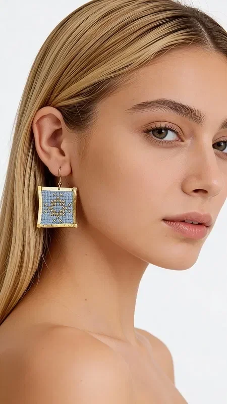 , The statement earrings with embroidered geometric patterns in light blue will become your favorite accessory for every special occasion. Designed by Greek Jewelry Designer Aikaterini Chalkiadaki, these striking handmade earrings combine the traditional art of embroidery with contemporary design.

The gold thread in a soft light blue shade creates a unique geometric motif that adds elegance and style to every look. These embroidered earrings have a square shape and medium size, ideal for making a statement without being overly heavy. Their detailed craftsmanship and folklore design make them special for evening outings, special events, or even bridal looks. Care for your earrings by storing them in a dry place and avoiding contact with water or chemical products to preserve their color.