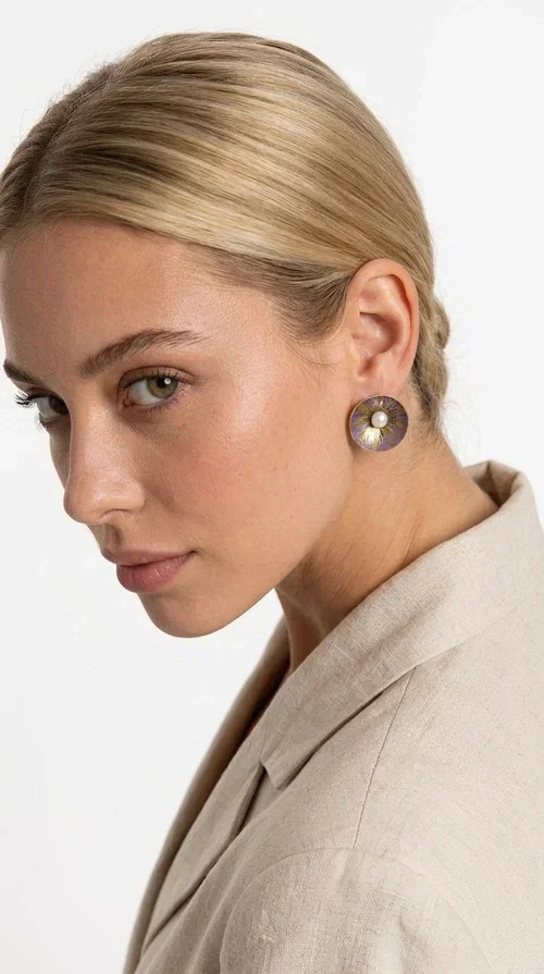 , Handmade purple stud earrings with pearls are an elegant choice for every woman seeking jewelry with character and feeling. Designed by Greek Jewelry Designer Aikaterini Chalkiadaki, these unique earrings combine refined aesthetics with the durability of brass and the warmth of handmade enamel, creating a result that truly stands out.

Each pair features a circular shape in a lilac-purple hue with golden brass details, while a natural pearl takes center stage, adding charm and femininity. The matte texture of the enamel combined with the soft shine of the pearl creates a contrast that makes the piece stand out both in everyday looks and in formal occasions, weddings and christenings.

Ideal as a gift or for personal use, they pair beautifully with minimal outfits, casual style, and formal looks alike. Their lightweight construction ensures comfort for everyday wear.