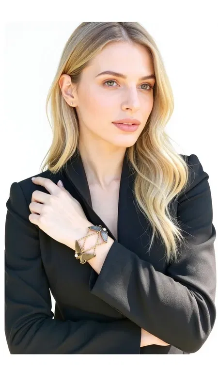 , This captivating butterfly statement bracelet combines artistic metalwork with lustrous freshwater pearls to create a truly mesmerizing piece. The intricate butterfly silhouettes are crafted from brass and treated with a sophisticated black patina finish that creates beautiful depth and character, with subtle bronze undertones that catch the light beautifully.
Each delicate butterfly is connected by elegant gold-tone chains and accented with genuine freshwater pearls that add a touch of classic elegance to the contemporary design. The contrast between the darkened metal butterflies and the luminous white pearls creates a stunning visual balance that's both bold and refined. The artisanal patina finish ensures that each piece has its own unique character and subtle variations.
This versatile statement piece elevates any outfit, whether you're dressing up for an evening event or adding artistic flair to your everyday style. The butterfly motif symbolizes transformation and freedom, making this bracelet perfect for those who appreciate meaningful jewelry with artistic depth. The adjustable chain design ensures comfortable wear while the substantial presence makes it ideal for layering or wearing as a standalone statement piece.
The handcrafted nature of this piece reflects traditional Greek jewelry-making techniques, where attention to detail and artistic expression are paramount. Each element is carefully assembled to create a harmonious composition that flows gracefully around the wrist.
To maintain the beautiful patina finish, avoid exposure to water and chemicals. Store in a dry place and clean gently with a soft cloth when needed.