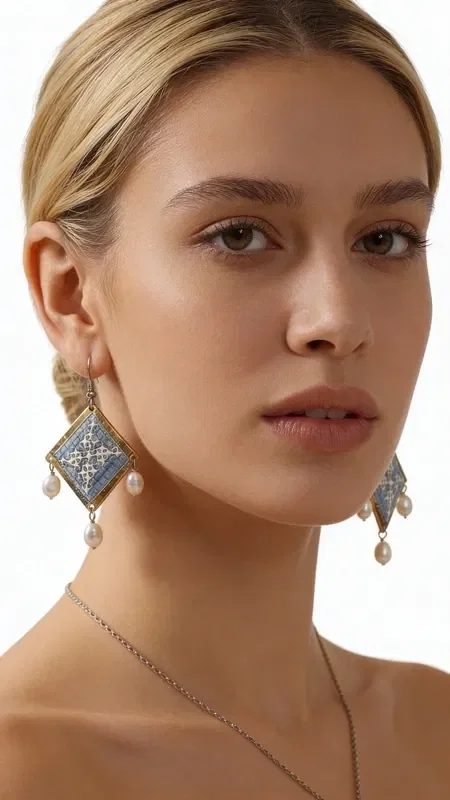, These statement embroidered earrings in light blue with geometric patterns made of gold thread are the ideal handmade jewelry piece to highlight your uniqueness. These impressive dangle earrings, designed by Greek Jewelry Designer Aikaterini Chalkiadaki, combine the traditional art of embroidery with a modern aesthetic.

The light blue hue combined with the gold thread creates a refined contrast that catches the eye. The geometric patterns add a contemporary touch, while the delicate pearls hanging from the base of the earrings add movement and femininity. Their folklore design makes them ideal for special occasions, from bridal looks to cocktail parties. Perfect earrings for weddings, christenings, and special events. Care for them with attention, avoiding contact with water and perfumes for a longer lifespan.