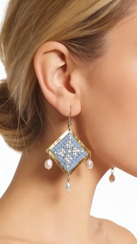 , These statement embroidered earrings in light blue with geometric patterns made of gold thread are the ideal handmade jewelry piece to highlight your uniqueness. These impressive dangle earrings, designed by Greek Jewelry Designer Aikaterini Chalkiadaki, combine the traditional art of embroidery with a modern aesthetic.

The light blue hue combined with the gold thread creates a refined contrast that catches the eye. The geometric patterns add a contemporary touch, while the delicate pearls hanging from the base of the earrings add movement and femininity. Their folklore design makes them ideal for special occasions, from bridal looks to cocktail parties. Perfect earrings for weddings, christenings, and special events. Care for them with attention, avoiding contact with water and perfumes for a longer lifespan.