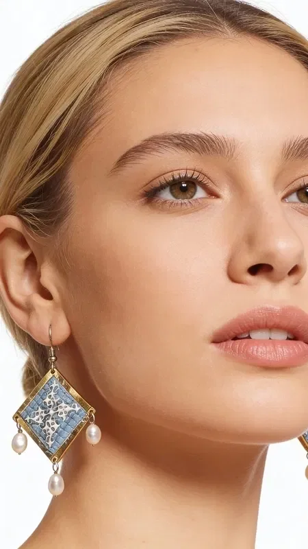 , These statement embroidered earrings in light blue with geometric patterns made of gold thread are the ideal handmade jewelry piece to highlight your uniqueness. These impressive dangle earrings, designed by Greek Jewelry Designer Aikaterini Chalkiadaki, combine the traditional art of embroidery with a modern aesthetic.

The light blue hue combined with the gold thread creates a refined contrast that catches the eye. The geometric patterns add a contemporary touch, while the delicate pearls hanging from the base of the earrings add movement and femininity. Their folklore design makes them ideal for special occasions, from bridal looks to cocktail parties. Perfect earrings for weddings, christenings, and special events. Care for them with attention, avoiding contact with water and perfumes for a longer lifespan.