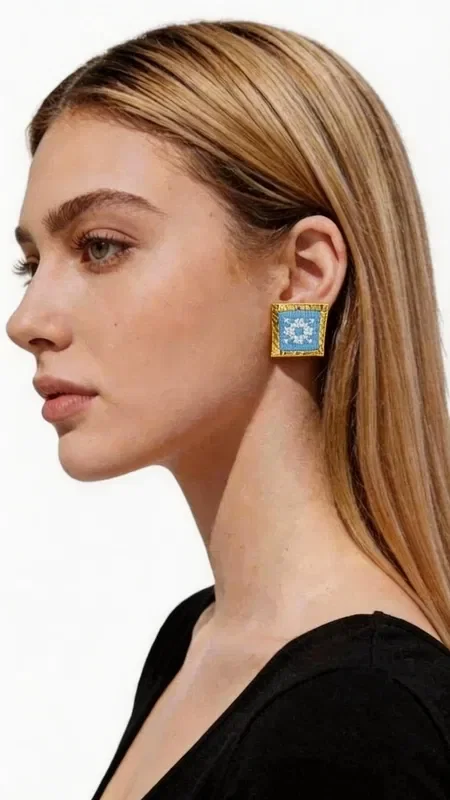 , These statement embroidered earrings with geometric patterns in light blue will add a unique character to every look. These striking handmade earrings, designed by Greek Jewelry Designer Aikaterini Chalkiadaki, combine the traditional art of embroidery with contemporary geometric design.

The gold thread framing the embroidered light blue fabric creates a refined contrast that catches the eye. The square shape with folklore embroidery highlights Greek tradition through a modern aesthetic.

Each earring is handmade with special attention to detail, guaranteeing the high quality and uniqueness of the piece. Ideal for striking appearances, wedding events, or everyday styling that wants to stand out. They pair perfectly with boho outfits, classic dresses, and modern casual looks.

Material: Brass, Fabric

Take care of them with gentle cleaning and store them in a dry place to preserve their shine.