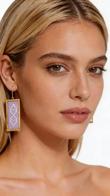 , Statement earrings featuring embroidered geometric designs in gold thread on a lilac background are the perfect choice for women who love striking and original jewelry. Designed by Greek Jewelry Designer Aikaterini Chalkiadaki, these handmade earrings combine the traditional art of embroidery with contemporary design.

Each earring is crafted with special attention to detail, using gold thread that forms beautiful geometric patterns in a soft lilac hue. Their rectangular shape and dangling style make them ideal for every occasion, from everyday outfits to special appearances and wedding events.

These embroidered earrings offer a unique sense of elegance and style, while their lightweight construction ensures comfortable wear all day long. Their folklore-inspired design reflects Greek tradition in a modern style.

Material: Brass, Fabric

Handle gently with a dry cloth and store in a safe place to preserve their beauty.