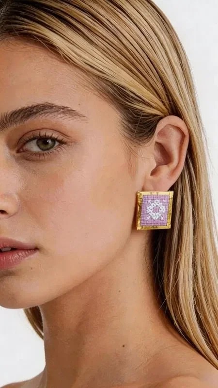, Embroidered statement earrings with geometric patterns in lilac color are the perfect choice for women who want to stand out with style and elegance. Designed by Greek Jewelry Designer Aikaterini Chalkiadaki, these striking handmade earrings combine the traditional art of embroidery with contemporary design. The square shape with intricate geometric motifs creates a unique visual effect that complements any look. The gold thread used in the embroidery adds shine and luxury, while the lilac color adds a touch of femininity and elegance.

These statement earrings are ideal for special events, evening outings, or even for a bridal look. They pair perfectly with monochrome outfits and add a bold splash of color to any ensemble.

Material: Brass, Fabric

To preserve their beauty, store the earrings in a dry place and avoid contact with moisture and perfumes.