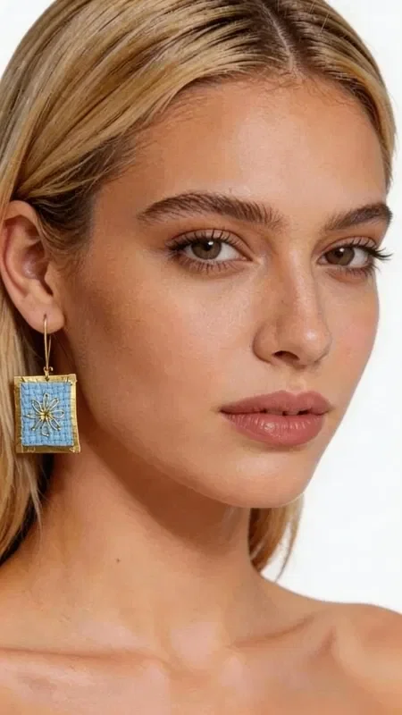 , The statement embroidered earrings with geometric patterns in gold thread on light blue are a unique combination of traditional craftsmanship and modern design. Designed by Greek Jewelry Designer Aikaterini Chalkiadaki, these striking handmade earrings enhance the elegance of any look with style and character. The delicate embroidery technique with gold thread creates a beautiful effect that subtly shimmers, while the light blue color offers a freshness that pairs perfectly with spring and summer outfits. The geometric patterns give a modern aesthetic, making these striking earrings an ideal choice for any occasion. The handmade embroidered earrings are perfect for weddings, christenings, summer parties and every special moment where you want to stand out. Pair them with white or blue clothing to highlight their light blue color. Material: Brass, Fabric. Take care of your earrings by storing them in a dry place, away from moisture and direct sunlight, to preserve their shine.