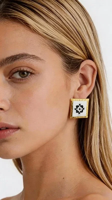 , The embroidered statement earrings with geometric patterns in gold thread on white fabric are the perfect choice for the woman who seeks striking and modern jewelry. Designed by Greek Jewelry Designer Aikaterini Chalkiadaki, they combine the traditional art of embroidery with contemporary aesthetics.

Each earring features a square shape with a refined geometric motif embroidered in gold thread on a white base. The folklore design creates a unique contrast that adds elegance and character to every look.

These handmade earrings are ideal for weddings, special occasions, or as an everyday statement piece. The high quality of craftsmanship and carefully selected materials guarantee durability and comfortable wear. Their lightweight design makes them suitable for all-day wear, while their size adds just the right amount of glamour without being overdone.

Material: Brass, Fabric

Take care of your earrings by avoiding contact with water and perfumes. Store them in a dry place to preserve their shine.