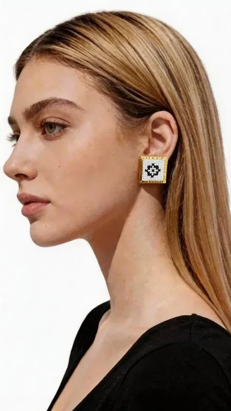 , The embroidered statement earrings with geometric patterns in gold thread on white fabric are the perfect choice for the woman who seeks striking and modern jewelry. Designed by Greek Jewelry Designer Aikaterini Chalkiadaki, they combine the traditional art of embroidery with contemporary aesthetics.

Each earring features a square shape with a refined geometric motif embroidered in gold thread on a white base. The folklore design creates a unique contrast that adds elegance and character to every look.

These handmade earrings are ideal for weddings, special occasions, or as an everyday statement piece. The high quality of craftsmanship and carefully selected materials guarantee durability and comfortable wear. Their lightweight design makes them suitable for all-day wear, while their size adds just the right amount of glamour without being overdone.

Material: Brass, Fabric

Take care of your earrings by avoiding contact with water and perfumes. Store them in a dry place to preserve their shine.