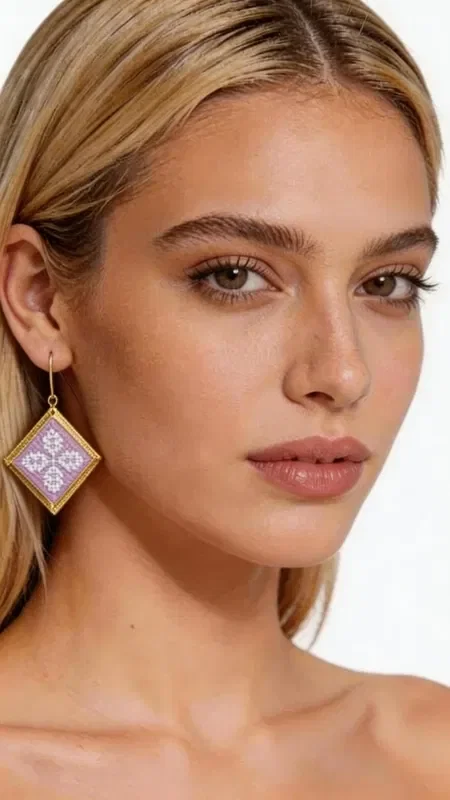 , These statement embroidered earrings in a soft lilac shade with geometric patterns in gold thread are the perfect choice for adding a touch of elegance and originality to your look. Designed by Greek Jewelry Designer Aikaterini Chalkiadaki, these handmade earrings combine the traditional technique of embroidery with contemporary design. Their square geometric shape is adorned with intricately embroidered motifs in a soft lilac tone, while the gold outline adds a luxurious touch. The folklore design with its detailed geometric patterns creates a unique piece of jewelry that stands out and complements both casual and formal looks. Ideal for women who love statement accessories, these earrings are perfect for special occasions, weddings, or for adding a splash of color to your everyday style.

Material: Brass, Fabric. To care for them, store the earrings in a dry place and avoid contact with water and chemicals.