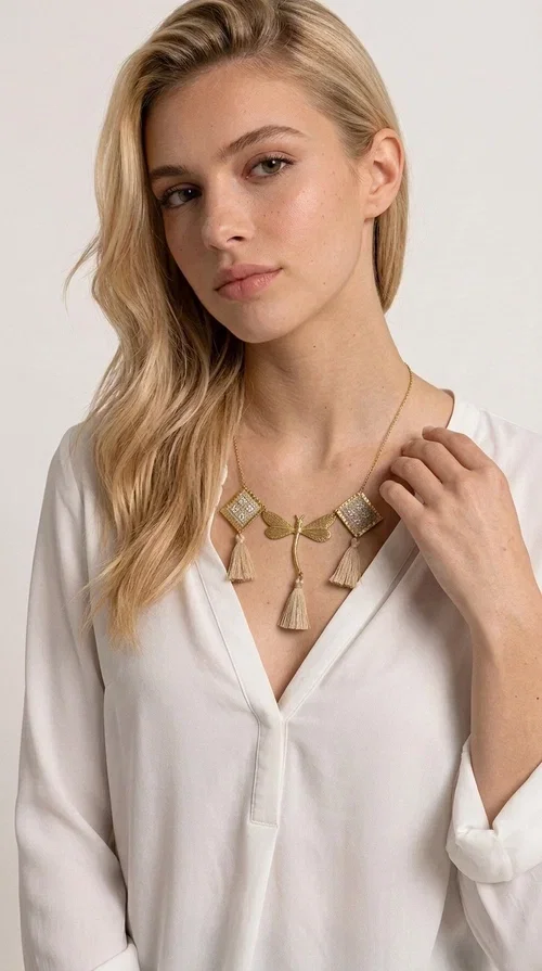 , The statement embroidered ivory necklace with geometric designs is a handmade piece that combines the traditional art of embroidery with a modern aesthetic, creating a result that instantly catches the eye. Designed by Greek Jewelry Designer Aikaterini Chalkiadaki, it is a tribute to folk art and Greek craftsmanship.

The necklace features gold-toned geometric brass elements in a diamond shape, adorned with delicate embroidered motifs in an ivory hue, evoking the rich aesthetic vocabulary of folklore. Among them, a gold metallic dragonfly-shaped element adds grace and movement to the piece. Three fabric tassels in an ivory-beige shade hang elegantly, giving depth and motion to the jewelry.

Ideal for summer outfits, boho and ethnic looks, as well as for elevating a simple dress or blouse. It pairs perfectly with linen clothing, maxi dresses, or casual summer looks.