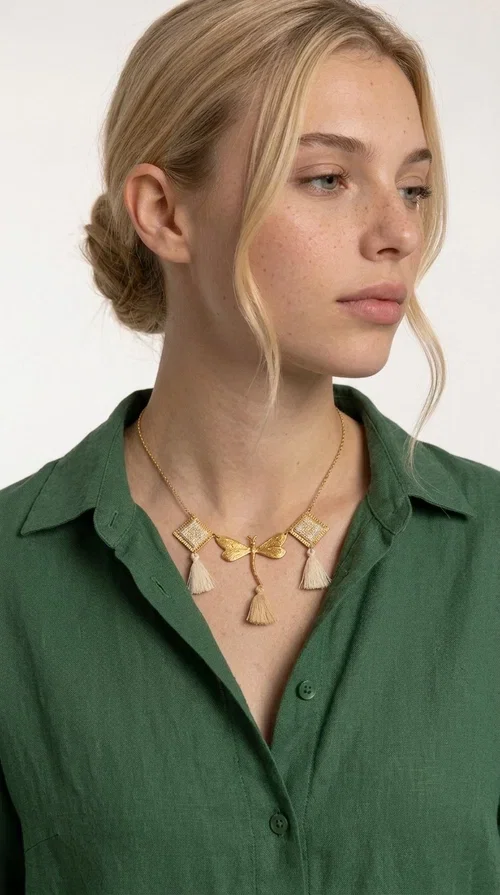 , An embroidered necklace that blends folk aesthetics with modern elegance — the Statement necklace KOL-4771 is the ideal choice for those seeking jewelry with character and warmth.

Designed by Greek Jewelry Designer Aikaterini Chalkiadaki, this necklace is a handmade work of art inspired by Greek folklore aesthetics. Made of brass and fabric, it features geometric embroidered motifs in gold tones alternating with a central butterfly motif, while four ivory fabric tassels add movement and boho-chic flair. The ivory and gold palette creates a timelessly elegant combination, suitable for every season.

Wear it with a white linen shirt or a simple dress to fully showcase its beauty. Ideal for summer looks, weddings, christenings, or even for everyday outings that call for something special.