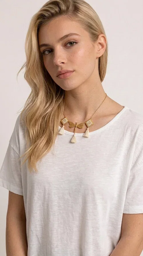 , An embroidered necklace that blends folk aesthetics with modern elegance — the Statement necklace KOL-4771 is the ideal choice for those seeking jewelry with character and warmth.

Designed by Greek Jewelry Designer Aikaterini Chalkiadaki, this necklace is a handmade work of art inspired by Greek folklore aesthetics. Made of brass and fabric, it features geometric embroidered motifs in gold tones alternating with a central butterfly motif, while four ivory fabric tassels add movement and boho-chic flair. The ivory and gold palette creates a timelessly elegant combination, suitable for every season.

Wear it with a white linen shirt or a simple dress to fully showcase its beauty. Ideal for summer looks, weddings, christenings, or even for everyday outings that call for something special.