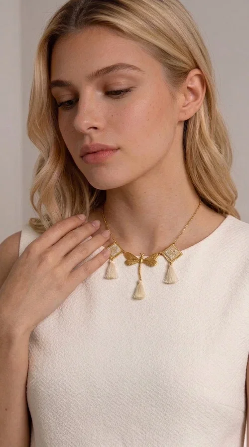 , An embroidered necklace that blends folk aesthetics with modern elegance — the Statement necklace KOL-4771 is the ideal choice for those seeking jewelry with character and warmth.

Designed by Greek Jewelry Designer Aikaterini Chalkiadaki, this necklace is a handmade work of art inspired by Greek folklore aesthetics. Made of brass and fabric, it features geometric embroidered motifs in gold tones alternating with a central butterfly motif, while four ivory fabric tassels add movement and boho-chic flair. The ivory and gold palette creates a timelessly elegant combination, suitable for every season.

Wear it with a white linen shirt or a simple dress to fully showcase its beauty. Ideal for summer looks, weddings, christenings, or even for everyday outings that call for something special.