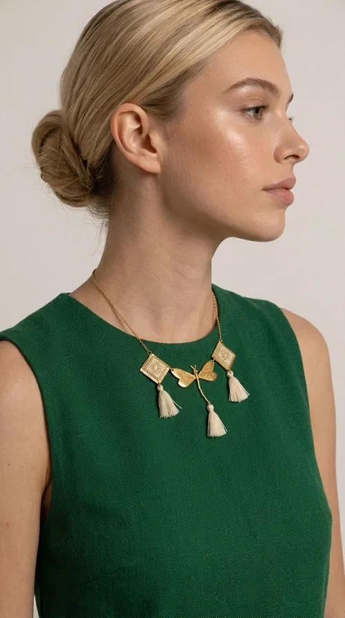 , An embroidered necklace that blends folk aesthetics with modern elegance — the Statement necklace KOL-4771 is the ideal choice for those seeking jewelry with character and warmth.

Designed by Greek Jewelry Designer Aikaterini Chalkiadaki, this necklace is a handmade work of art inspired by Greek folklore aesthetics. Made of brass and fabric, it features geometric embroidered motifs in gold tones alternating with a central butterfly motif, while four ivory fabric tassels add movement and boho-chic flair. The ivory and gold palette creates a timelessly elegant combination, suitable for every season.

Wear it with a white linen shirt or a simple dress to fully showcase its beauty. Ideal for summer looks, weddings, christenings, or even for everyday outings that call for something special.