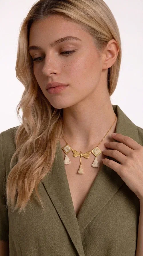, An embroidered necklace that blends folk aesthetics with modern elegance — the Statement necklace KOL-4771 is the ideal choice for those seeking jewelry with character and warmth.

Designed by Greek Jewelry Designer Aikaterini Chalkiadaki, this necklace is a handmade work of art inspired by Greek folklore aesthetics. Made of brass and fabric, it features geometric embroidered motifs in gold tones alternating with a central butterfly motif, while four ivory fabric tassels add movement and boho-chic flair. The ivory and gold palette creates a timelessly elegant combination, suitable for every season.

Wear it with a white linen shirt or a simple dress to fully showcase its beauty. Ideal for summer looks, weddings, christenings, or even for everyday outings that call for something special.