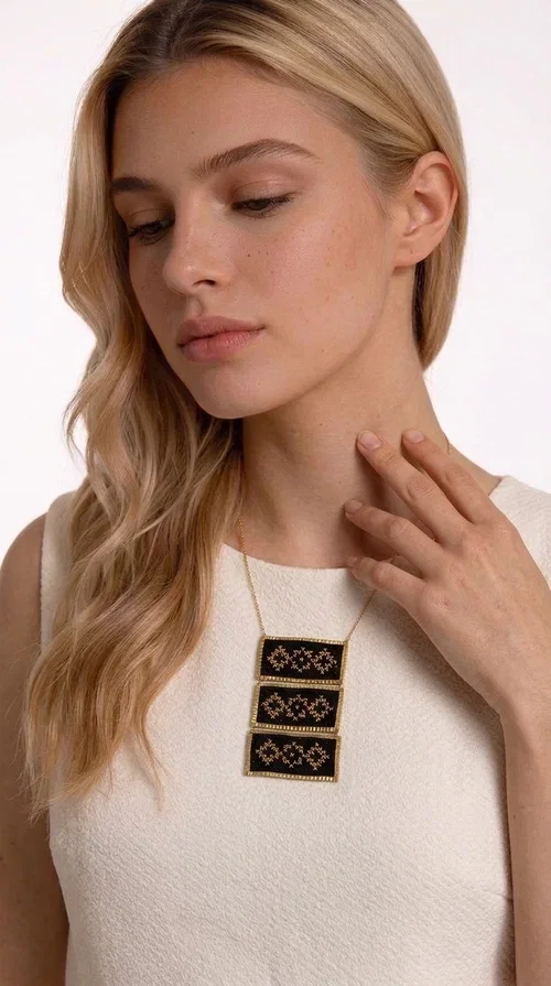 , An embroidered necklace that combines traditional Greek aesthetics with modern fashion — the Statement necklace KOL-4774 is a handmade creation that instantly catches the eye.

Designed by Greek Jewelry Designer Aikaterini Chalkiadaki, this necklace features three rectangular fabric plaques in deep black, adorned with gold-toned embroidered geometric designs inspired by Greek folk tradition. The frame of each plaque, made of gold-toned brass, gives the piece a rich, striking presence. The accompanying brass chain keeps the composition light on the neck, while the overall look exudes a unique blend of ethnic and contemporary style.

Ideal for women who love statement jewelry and want to elevate simple outfits — a linen shirt, a black dress, or even a casual look — with a wonderful touch of individuality. Perfect for nights out, events, weddings, or everyday wear when you want to stand out.